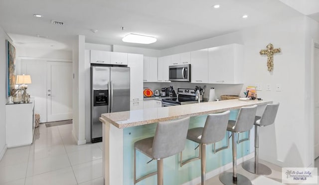 kitchen featuring white cabinetry, stainless steel appliances, a breakfast bar, and kitchen peninsula