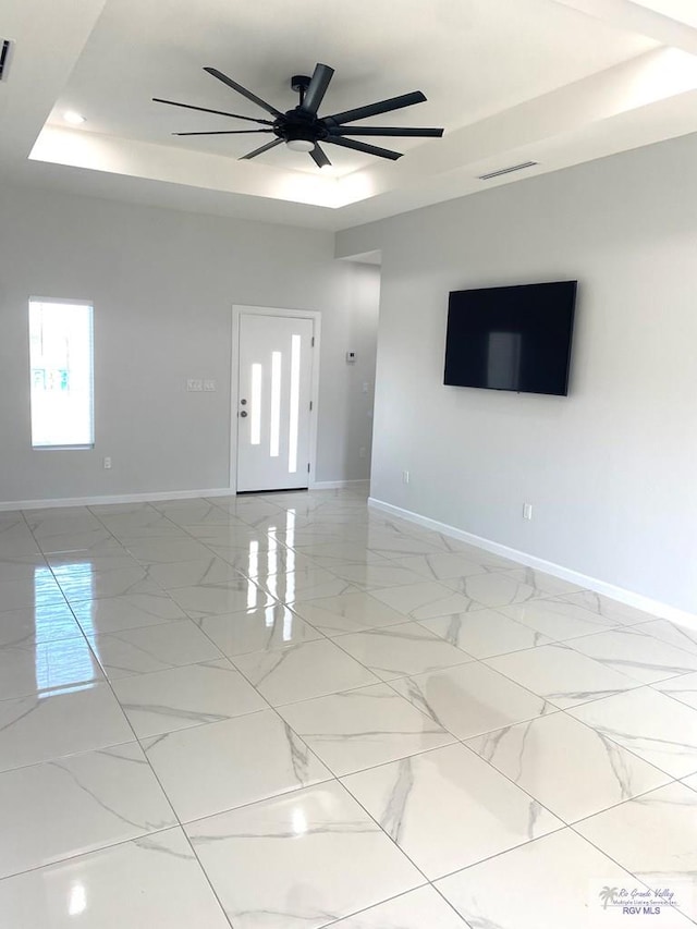 unfurnished room featuring a raised ceiling and ceiling fan