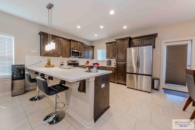 kitchen featuring stainless steel appliances, a breakfast bar area, a peninsula, and light countertops