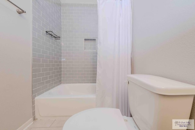 bathroom with toilet, tile patterned flooring, baseboards, and shower / tub combo with curtain