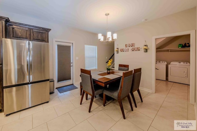 dining area featuring light tile patterned floors, baseboards, washing machine and dryer, and a notable chandelier