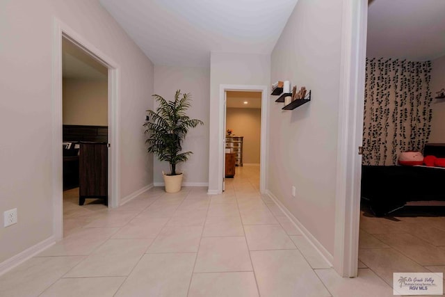 corridor with light tile patterned floors and baseboards