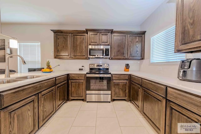 kitchen featuring light tile patterned floors, a sink, light countertops, appliances with stainless steel finishes, and decorative backsplash