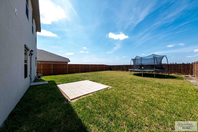 view of yard with a patio area, a fenced backyard, and a trampoline