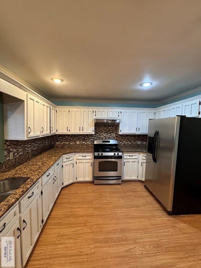 kitchen featuring dark stone countertops, white cabinetry, stainless steel appliances, and light hardwood / wood-style floors