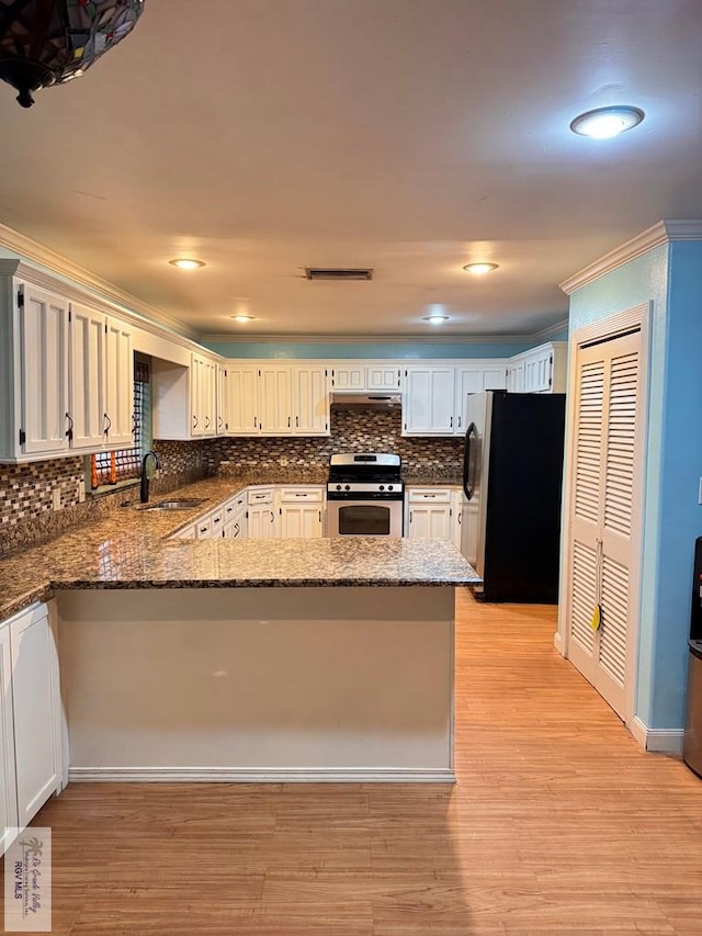 kitchen featuring sink, light hardwood / wood-style flooring, kitchen peninsula, decorative backsplash, and appliances with stainless steel finishes