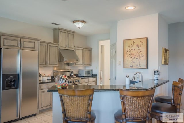 kitchen featuring under cabinet range hood, dark countertops, visible vents, and stainless steel built in fridge