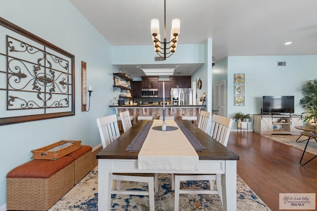 dining area with visible vents, baseboards, wood finished floors, and a notable chandelier