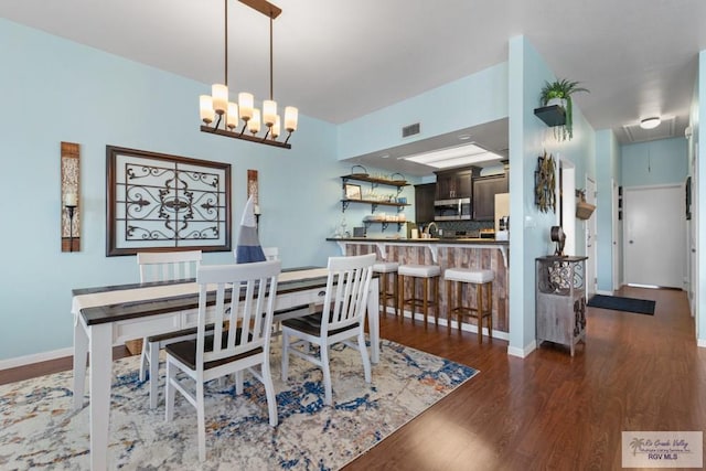 dining space with an inviting chandelier, attic access, baseboards, dark wood-type flooring, and visible vents