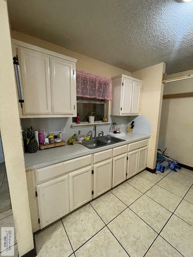 kitchen with sink, a textured ceiling, and light tile patterned floors