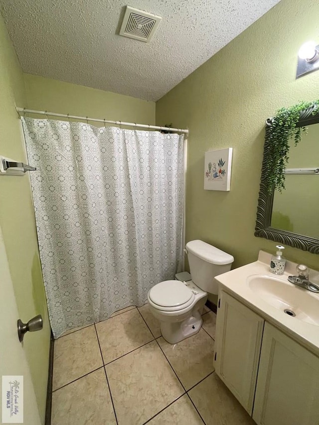 bathroom featuring tile patterned flooring, vanity, a textured ceiling, and toilet