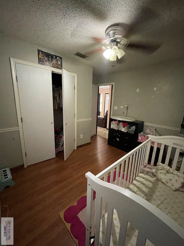 bedroom with ceiling fan, a closet, dark hardwood / wood-style floors, and a textured ceiling