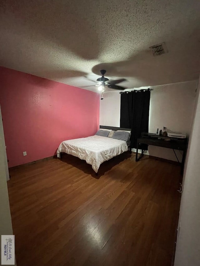 bedroom featuring ceiling fan, dark hardwood / wood-style floors, and a textured ceiling