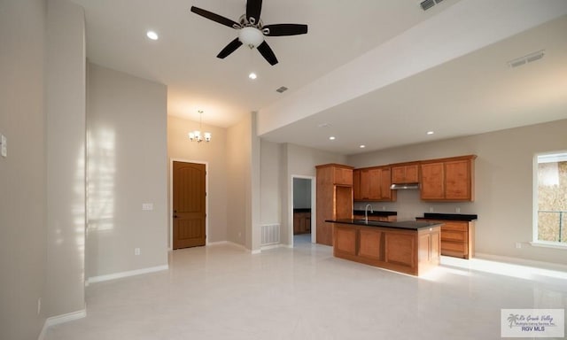 kitchen featuring ceiling fan with notable chandelier, a kitchen island, sink, and pendant lighting