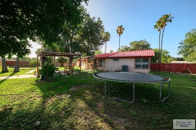 307 W Boone Ave, Pharr, TX 78577 - back of house featuring a trampoline, a fenced backyard, a metal roof, and stucco siding