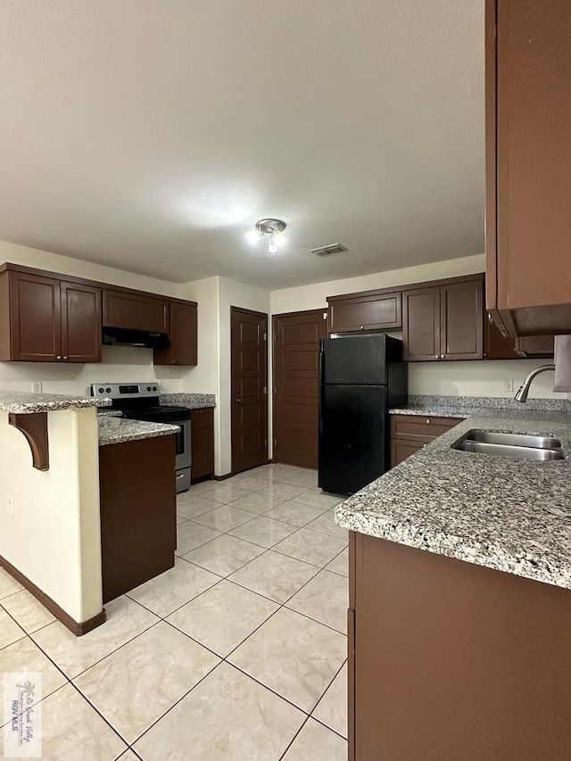 kitchen featuring sink, electric range, light stone counters, dark brown cabinetry, and black fridge