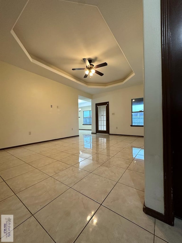 unfurnished room with light tile patterned floors, a raised ceiling, and ceiling fan