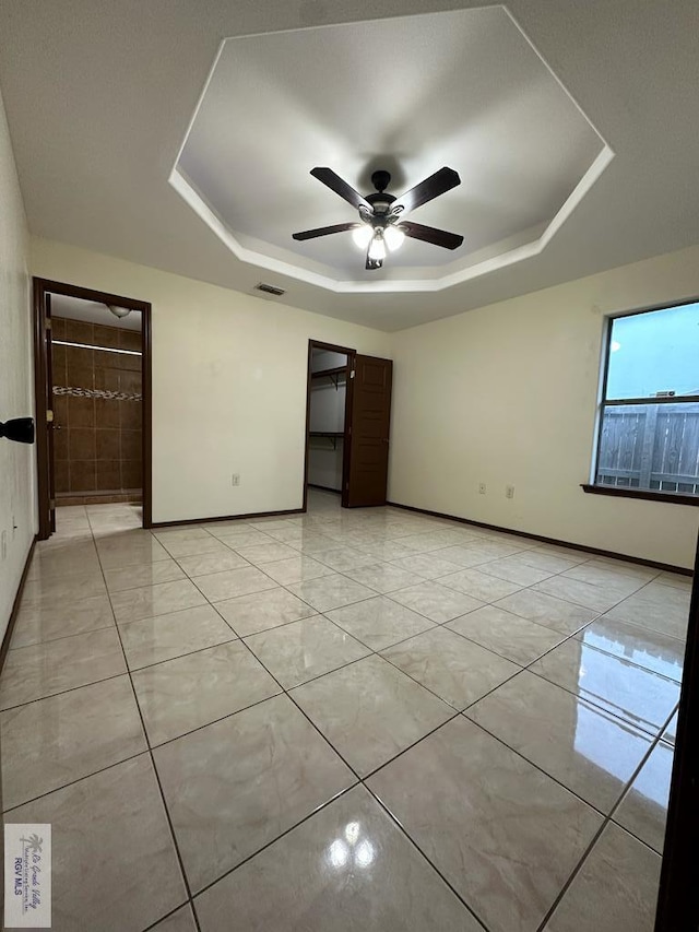 spare room featuring ceiling fan, a raised ceiling, and light tile patterned floors