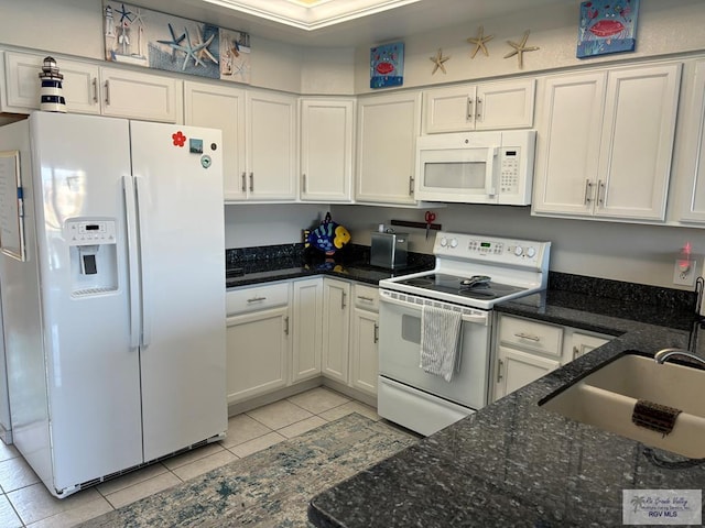 kitchen with white appliances, sink, dark stone countertops, white cabinetry, and light tile patterned flooring