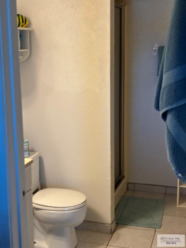 bathroom with tile patterned flooring, vanity, toilet, and a shower with door