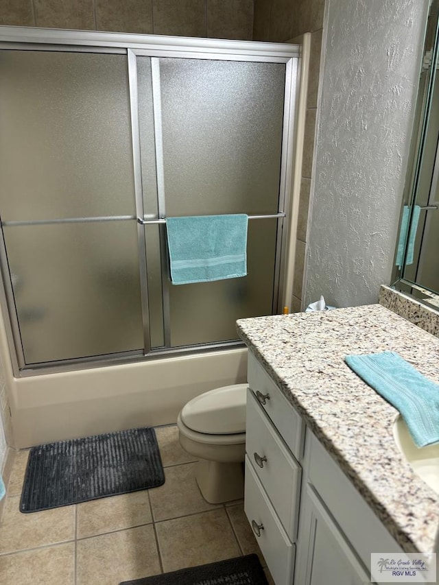 full bathroom featuring tile patterned floors, vanity, toilet, and enclosed tub / shower combo