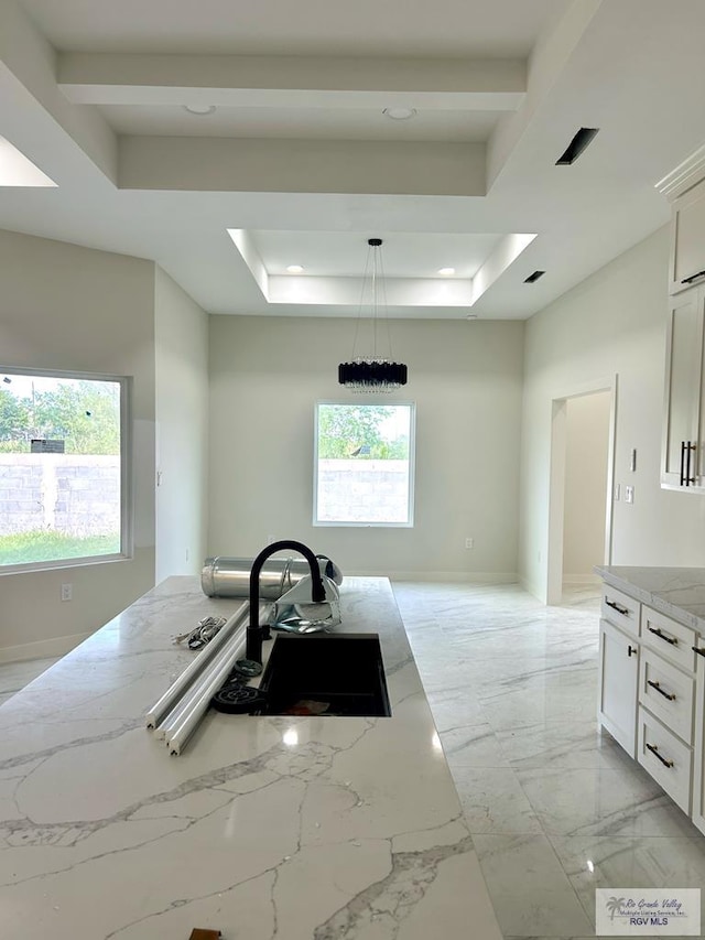 kitchen with light stone counters, white cabinets, and a tray ceiling