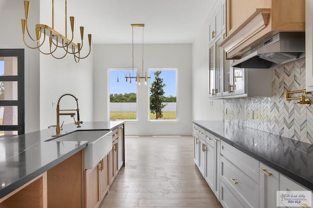 1305 Thacker Ln, Harlingen, TX 78552 - kitchen featuring a sink, a chandelier, backsplash, light wood finished floors, and range hood