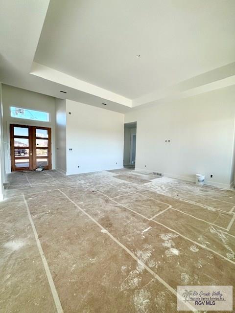 unfurnished living room with a tray ceiling and french doors