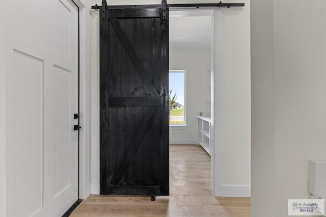 1305 Thacker Ln, Harlingen, TX 78552 - hall featuring a barn door, light wood finished floors, and baseboards