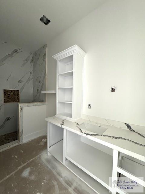 interior space with a marble finish shower and vanity