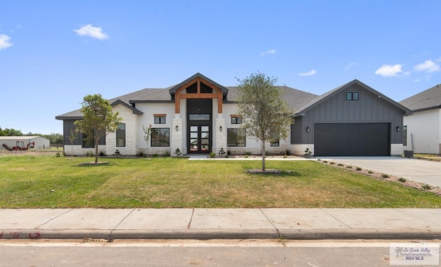 1305 Thacker Ln, Harlingen, TX 78552 - view of front of home with board and batten siding, driveway, a garage, a front lawn, and stone siding