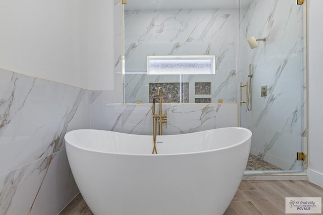 1305 Thacker Ln, Harlingen, TX 78552 - bathroom with tile walls, a marble finish shower, wood finished floors, and a soaking tub