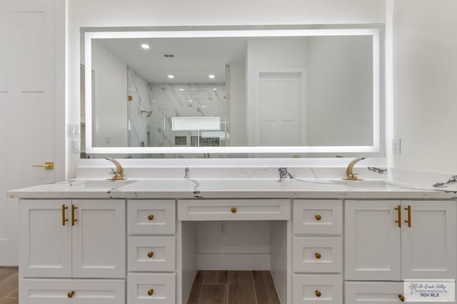 1305 Thacker Ln, Harlingen, TX 78552 - bathroom featuring a marble finish shower, double vanity, and wood finished floors