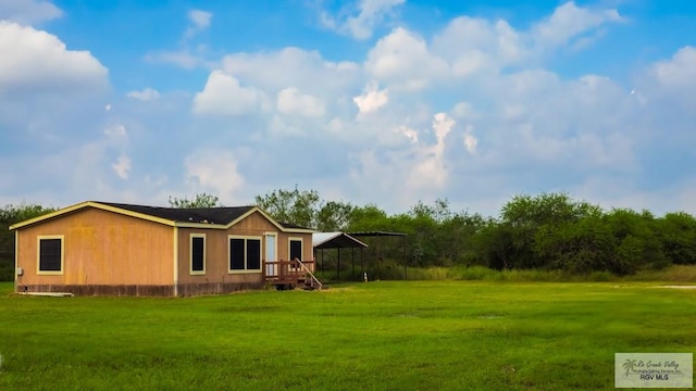 back of property with a carport and a lawn