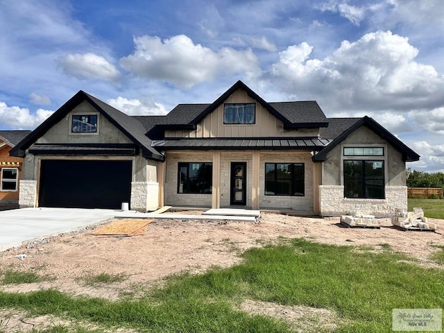 2625 Marky St, Harlingen, TX 78552 - view of front of house with stone siding, concrete driveway, board and batten siding, a standing seam roof, and covered porch