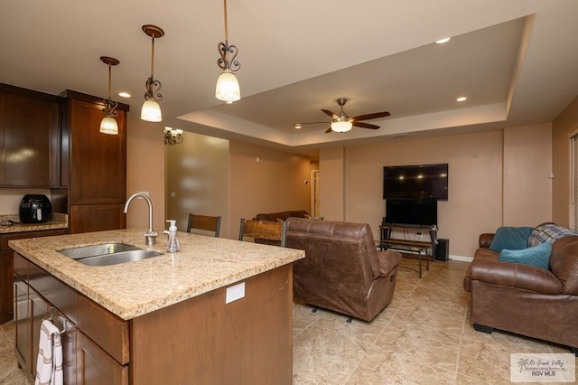 23314 Grapefruit Ave, Harlingen, TX 78552 - kitchen featuring a raised ceiling, open floor plan, a ceiling fan, a center island with sink, and pendant lighting
