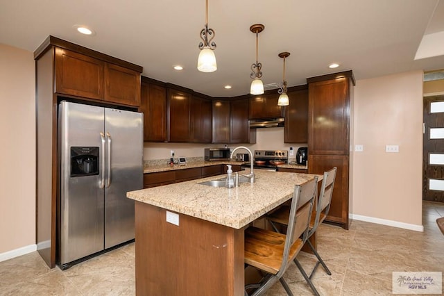23314 Grapefruit Ave, Harlingen, TX 78552 - kitchen with stainless steel appliances, under cabinet range hood, light stone counters, recessed lighting, and decorative light fixtures