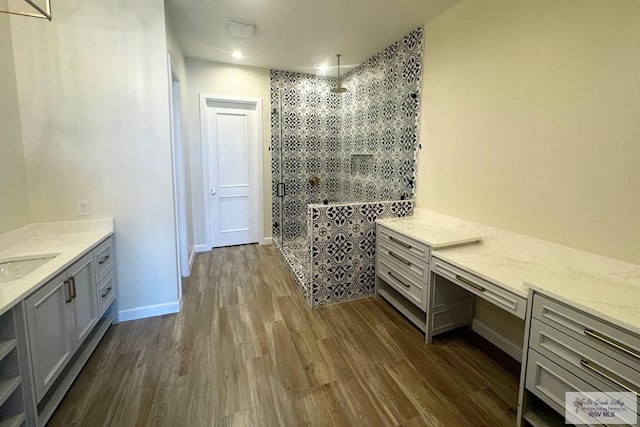 bathroom featuring hardwood / wood-style floors, vanity, and tiled shower