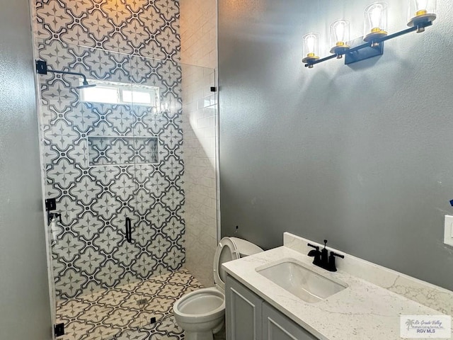 bathroom featuring vanity, a shower with shower door, and toilet