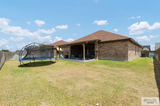 16620 W Duff Ct, Harlingen, TX 78552 - rear view of house featuring a trampoline, brick siding, a fenced backyard, and a patio area