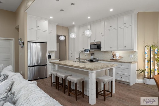 16620 W Duff Ct, Harlingen, TX 78552 - kitchen with appliances with stainless steel finishes, a kitchen breakfast bar, backsplash, white cabinets, and recessed lighting