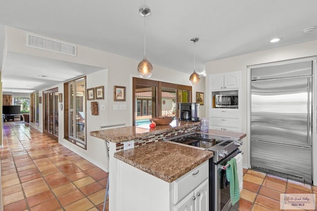 kitchen featuring visible vents, a kitchen island, white cabinetry, appliances with stainless steel finishes, and hanging light fixtures