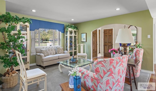 living area with recessed lighting, arched walkways, and baseboards