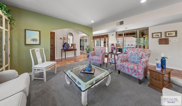 carpeted living room featuring arched walkways, visible vents, recessed lighting, and tile patterned flooring