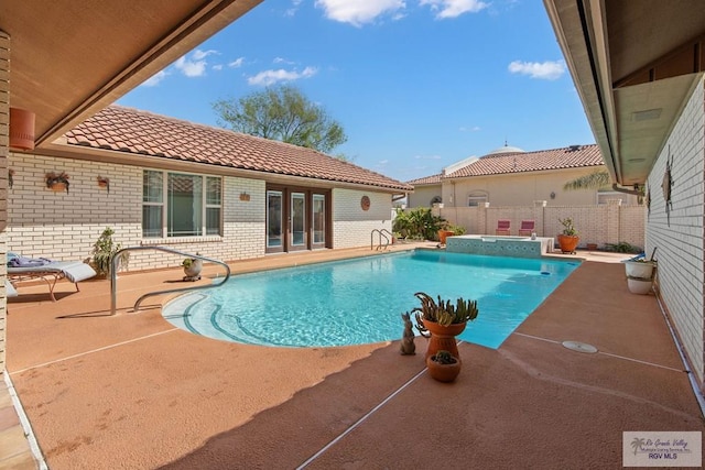 view of swimming pool featuring a patio, fence, a fenced in pool, and an in ground hot tub