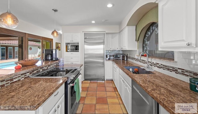 kitchen featuring a sink, decorative light fixtures, tasteful backsplash, white cabinetry, and appliances with stainless steel finishes