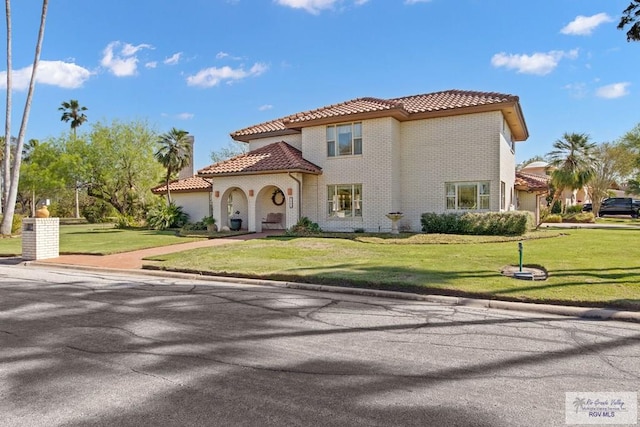 mediterranean / spanish home featuring brick siding, a garage, a tile roof, and a front lawn