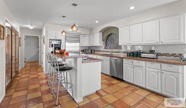 kitchen with a breakfast bar, decorative backsplash, white cabinets, appliances with stainless steel finishes, and a center island