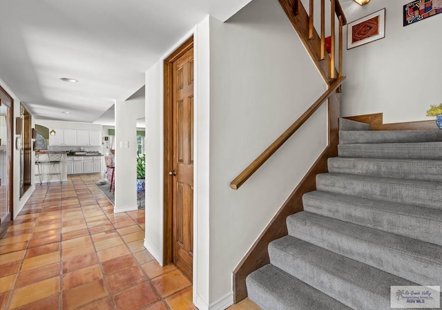 staircase featuring tile patterned floors and baseboards