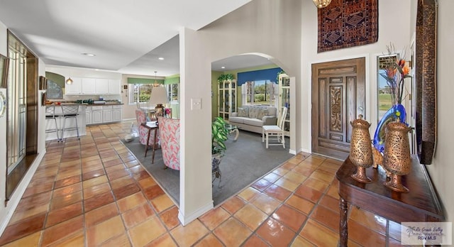 foyer with recessed lighting, light tile patterned flooring, baseboards, and arched walkways